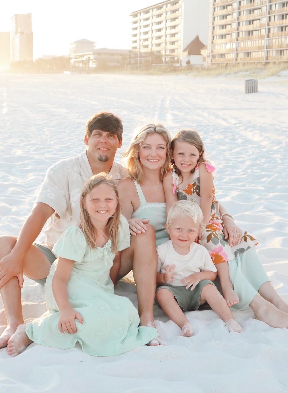 Family laughing on the shoreline at sunset